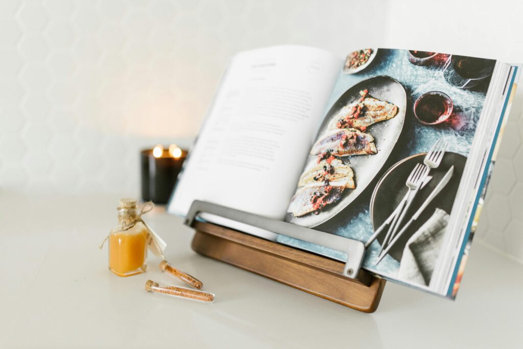 pexels-photo-8581015-8581015 Open cookbook with a delicious fish recipe, styled with candlelight ambience.